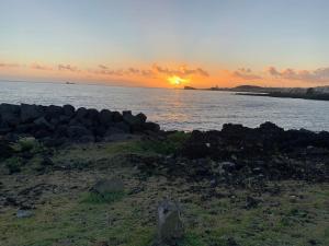 una puesta de sol sobre un cuerpo de agua con rocas en Cantinho do Pópulo en Ponta Delgada