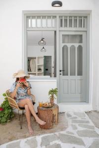 a woman in a hat sitting in a chair on a patio at Adamas Studios in Naxos Chora
