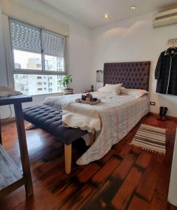 1 dormitorio con 1 cama grande y un banco azul en Almagro 3 ambientes/Cochera en Buenos Aires