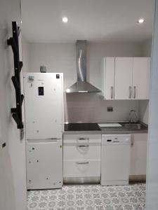 a kitchen with white cabinets and a white refrigerator at Sitges Oasis in Sitges