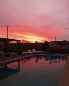 una piscina con sillas y una puesta de sol en el fondo en Cabañas Club Mediterraneo en Quillón