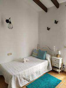 a white bedroom with a bed and a blue rug at Casa rural La Matriche in Mijas
