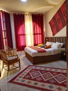 a bedroom with two beds and a chair and red curtains at Petra fort hotel in Wadi Musa