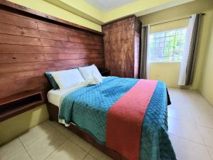 a bedroom with a bed with a wooden wall at Papaya Grove Mountainview Condos in Hope