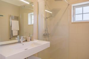 ein weißes Bad mit einem Waschbecken und einer Dusche in der Unterkunft Penthouse Casa Astona in Amoreira