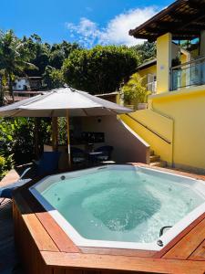 uma piscina com um guarda-sol num pátio em Casa Amarela em Angra dos Reis