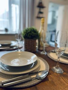 a wooden table with a plate and two wine glasses at Railway House - By EazyStays in Crewe