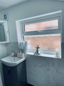 La salle de bains est pourvue d'un lavabo et d'une fenêtre. dans l'établissement Railway House - By EazyStays, à Crewe