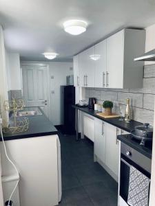 a kitchen with white cabinets and black counter tops at Railway House - By EazyStays in Crewe