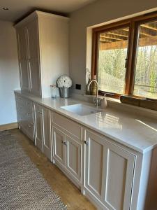 a large kitchen with a sink and a window at Hideaway Barn Coltishall in Coltishall