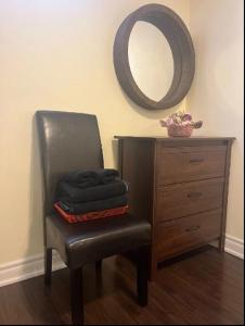 a black chair with a mirror and a dresser at Cozy & Spacious Suite with Private Bathroom near Toronto Airport ! in Mississauga