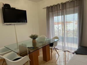 a glass desk with a television on a wall in a room at Confort Apartment 2 Bedrooms in Alhos Vedros