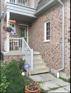 ein Backsteinhaus mit einer weißen Treppe und einer Tür in der Unterkunft Cozy & Spacious Suite with Private Bathroom near Toronto Airport ! in Mississauga