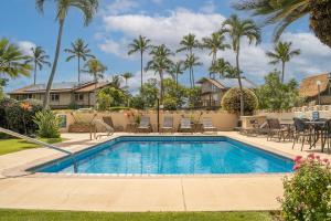 a swimming pool with patio furniture and palm trees at Wailana Sands 206 in Kihei