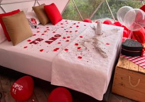 Chinauta_Eco_Glamping في فوساغاسوغا: سرير مغطى ببتلات الورد الأحمر في الغرفة