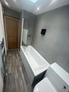a white bathroom with a tub and a toilet at Stylish 2 bed apartment. in Birmingham
