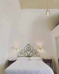 1 dormitorio con cama blanca y cabecero de plata en La Baia di Napoli, en Capri