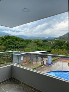 聖赫羅尼莫的住宿－Apartasol San Jeronimo Antioquia，享有游泳池和山脉美景的阳台。