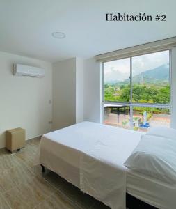 聖赫羅尼莫的住宿－Apartasol San Jeronimo Antioquia，卧室设有白色的床和大窗户