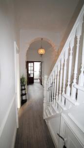 a hallway with white stairs and a chandelier at Heaton - Great Customer Feedback - 5 Large Bedrooms - Period Property - Refurbished Throughout in Newcastle upon Tyne