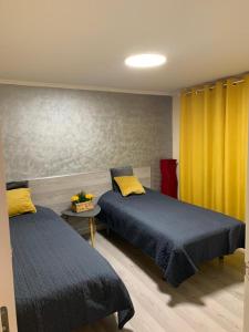 2 Betten in einem Zimmer mit gelben Vorhängen in der Unterkunft Aquí Me Quedo in Logroño