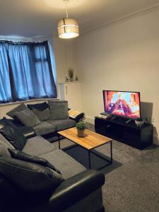 uma sala de estar com um sofá e uma televisão de ecrã plano em Railway House - By EazyStays em Crewe