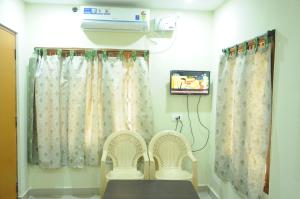 um quarto com duas cadeiras e um aquecedor e cortinas em Hotel Agarala Residency em Tirupati