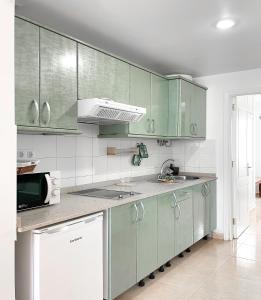 kuchnia z zielonymi szafkami i zlewem w obiekcie Aurora House w Corralejo