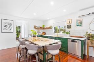 a kitchen with green cabinets and a green island with stools at Cooee Bay Beach House in Yeppoon