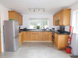 eine Küche mit Holzschränken und einem Kühlschrank aus Edelstahl in der Unterkunft Rowarth in Pwllheli