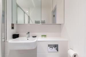 ein weißes Badezimmer mit einem Waschbecken und einem Spiegel in der Unterkunft Coral - 2 Bedroom Flat in Bracknell