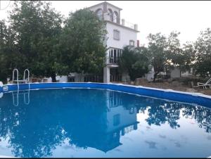 une grande piscine en face d'une maison dans l'établissement Cortijo la Umbria, à Villanueva de Algaidas