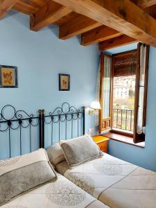 2 letti in una camera da letto con pareti blu e finestra di Casa Rural el Quemao a Villoslada de Cameros