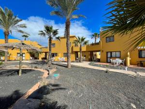 ośrodek z palmami i żółtym budynkiem w obiekcie Aurora House w Corralejo