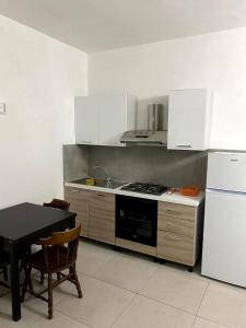 a kitchen with white cabinets and a table and a stove at Casa vacanza le tre palme in Floridia