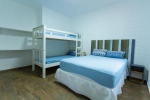 a bedroom with a bunk bed and a white bunk bed at Paraíso Azul - Praia de Barequeçaba in Barequeçaba
