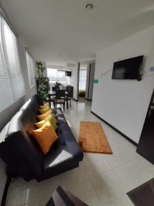 una sala de estar con un sofá de cuero negro con almohadas amarillas en Apartamentos para tus vacaciones, en Armenia