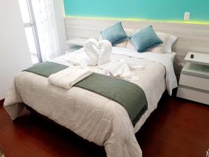a bedroom with a bed with white sheets and blue pillows at Hermoso apartamento Unidos En Familia en JESÚS MARÍA in Lima