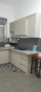 a kitchen with white cabinets and a table and stool at Kerian Putra Muslimstay in Parit Buntar