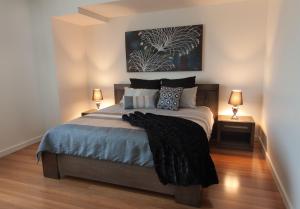 a bedroom with a large bed with two lamps at Amaroo in Queenscliff