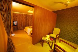 a bedroom with a bed and a chair and a mirror at Hotel Chenduran Park in Dindigul