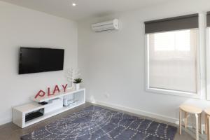 a living room with a flat screen tv on a white wall at Amaroo in Queenscliff