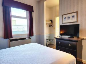 um quarto de hotel com uma cama e uma televisão de ecrã plano em The Steveston Cafe & Hotel em Richmond