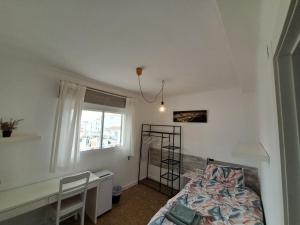 a bedroom with a bed and a desk and a window at Carmen Guest House in Benalmádena