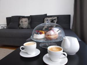 een tafel met een dienblad donuts en kopjes koffie bij Apartament Rondo ONZ in Warschau