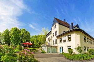 ein großes weißes Gebäude mit schwarzem Dach in der Unterkunft Dorint Parkhotel Siegen in Siegen