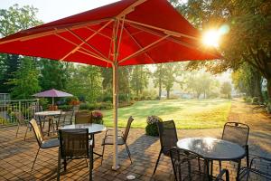 een patio met tafels en stoelen onder een rode parasol bij Dorint Parkhotel Siegen in Siegen