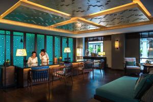 two people standing at a bar in a restaurant at Phuket Marriott Resort and Spa, Nai Yang Beach in Nai Yang Beach