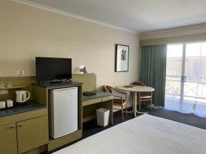 una camera d'albergo con letto e tavolo con TV di Stay at Alice Springs Hotel a Alice Springs