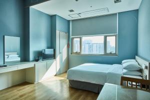 1 dormitorio con paredes azules, 1 cama y 1 mesa en Provista Hotel, en Seúl